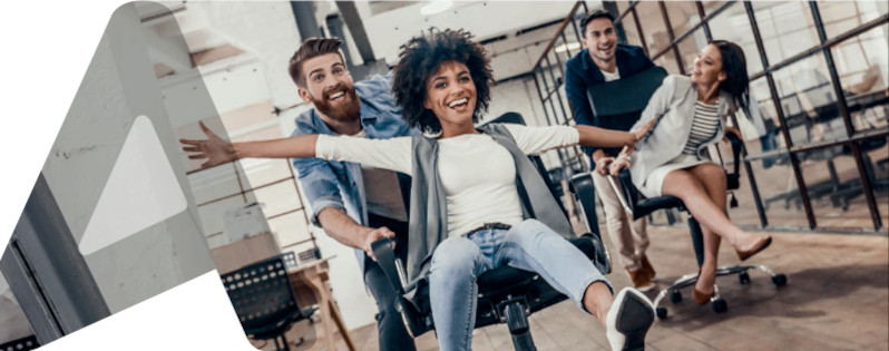 zwei Männer schieben zwei Frauen in Bürostühlen auf Rädern